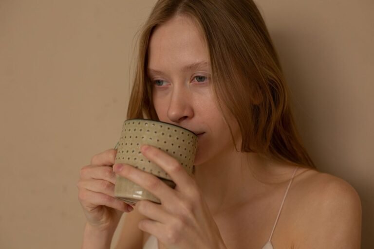 Mulher segurando uma xícara de café quente perto da janela ensolarada