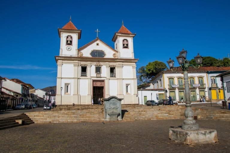 Família brasileira conversa sorrindo na escadaria de uma igreja sob a luz do dia