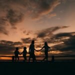 Pessoas reunidas em momento de afeto e paz ao pôr do sol.