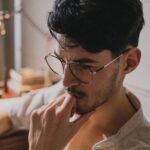 Homem observa planta na escrivaninha, à luz natural